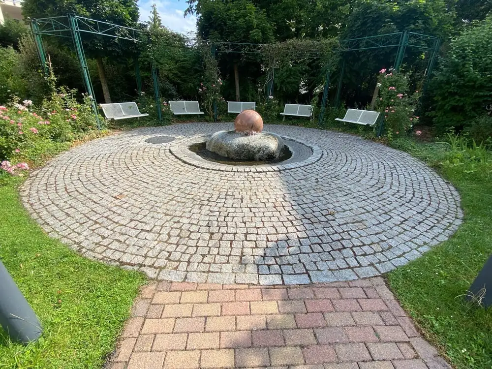 Brunnenanlage mit Marmorkugel, Bänken und Rasen in einer Wohnanlage