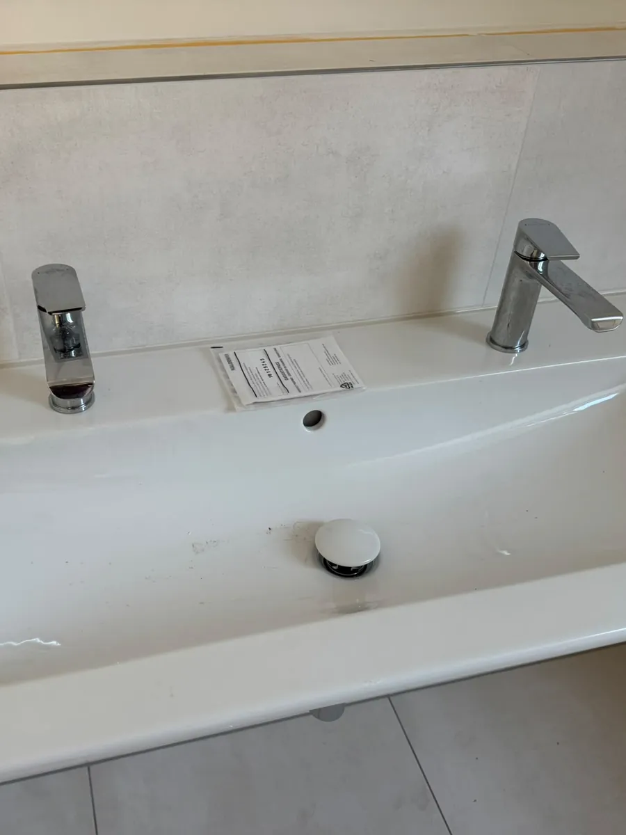 Doppelwaschbecken im Neubau vor der Reinigung, mit Baustaub und Garantiezettel