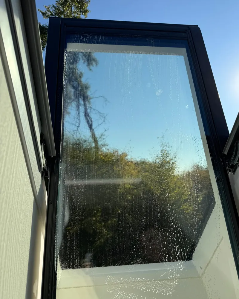 Glas eines Dachfensters wird von außen gereinigt