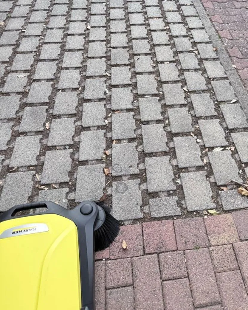Kehrmaschine auf einem gepflasterten Gehweg