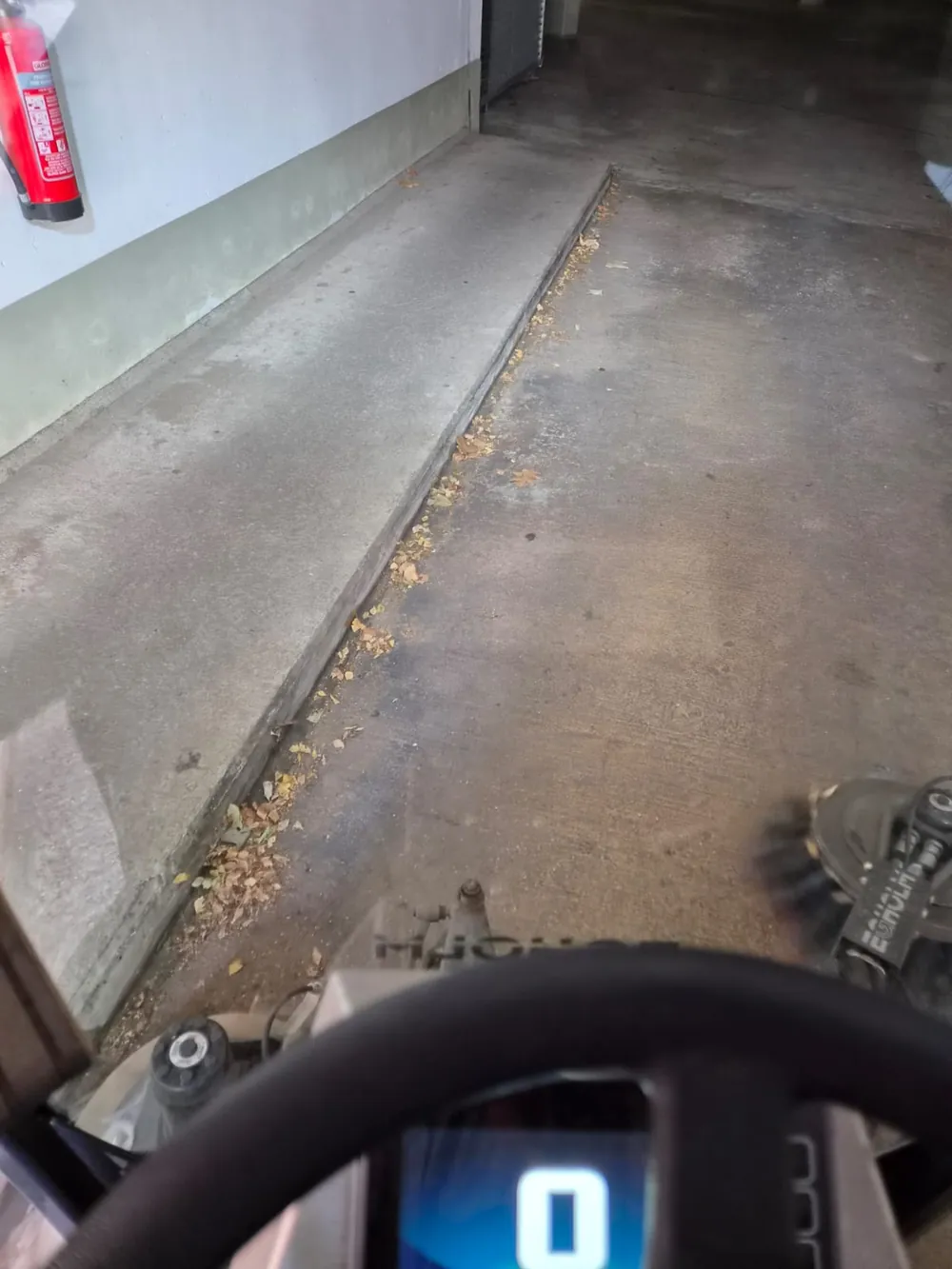 Kehrmaschine kehrt Laub an einer Kante in einer Tiefgarage
