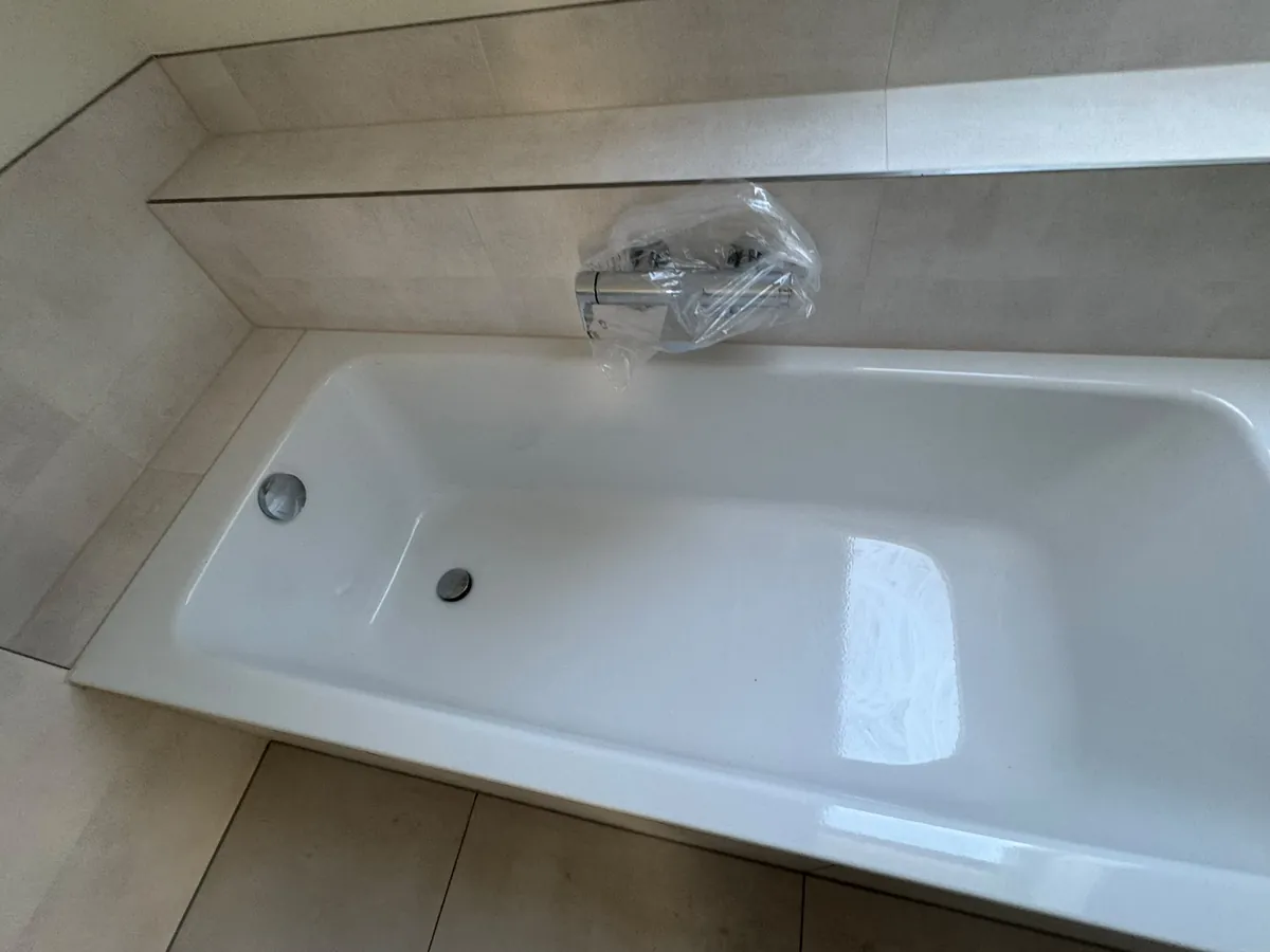 Saubere Badewanne in einem Neubau, die Armatur noch in Schutzfolie